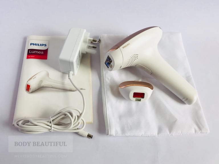 The contents of the Lumea Advnaced laid out; user manual, power cable, storage pouch, cleaning cloth, Lumea device with body attachment and facial attachment.
