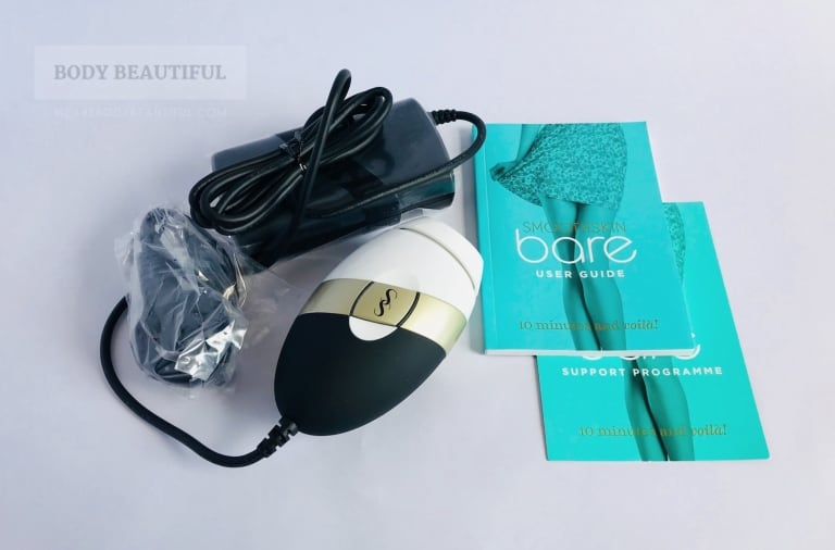 Photo of the box contents:  the compact Smoothskin Bare device and power pack, country specific power plug, user manual booklet and support programme card.